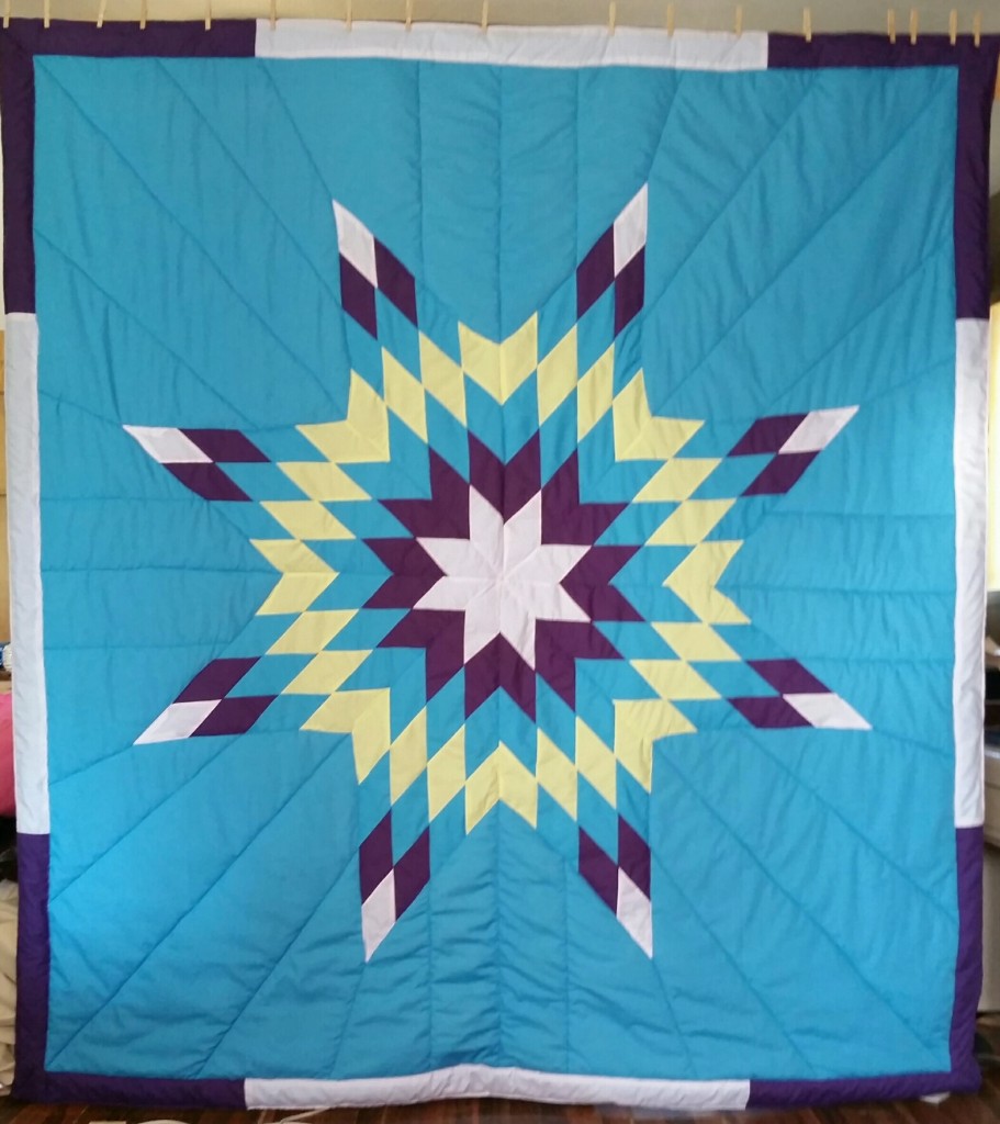 Turqoise Star Blanket with white, purple, yellow and turquoise star and border.