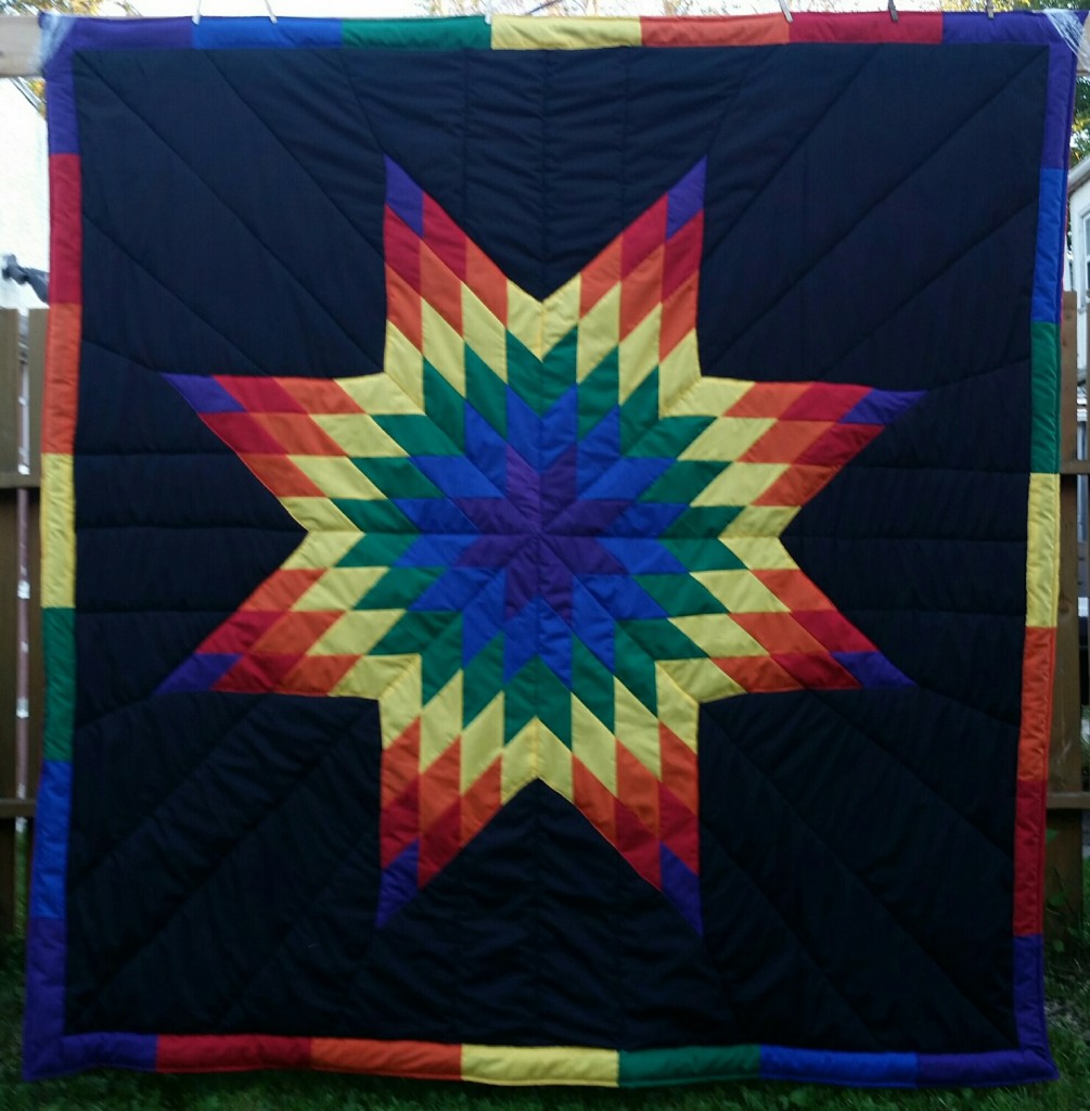 Black blanket with rainbow colors in the star (purple, blue, green, yellow, orange, red) and rainbow border